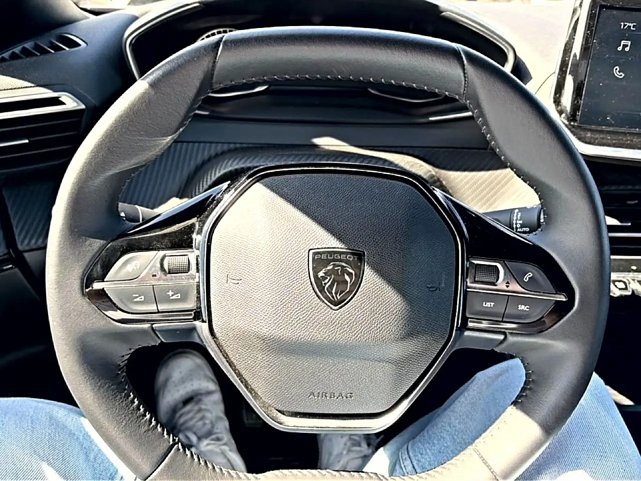 Vue rapprochée du volant cuir noir du Peugeot 2008 2025 avec commandes multifonctions et logo lion central.