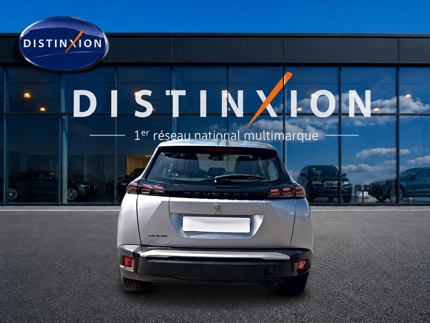 Vue arrière d'un Peugeot 2008 gris 2025 garé devant une vitrine avec logo Distinxion.