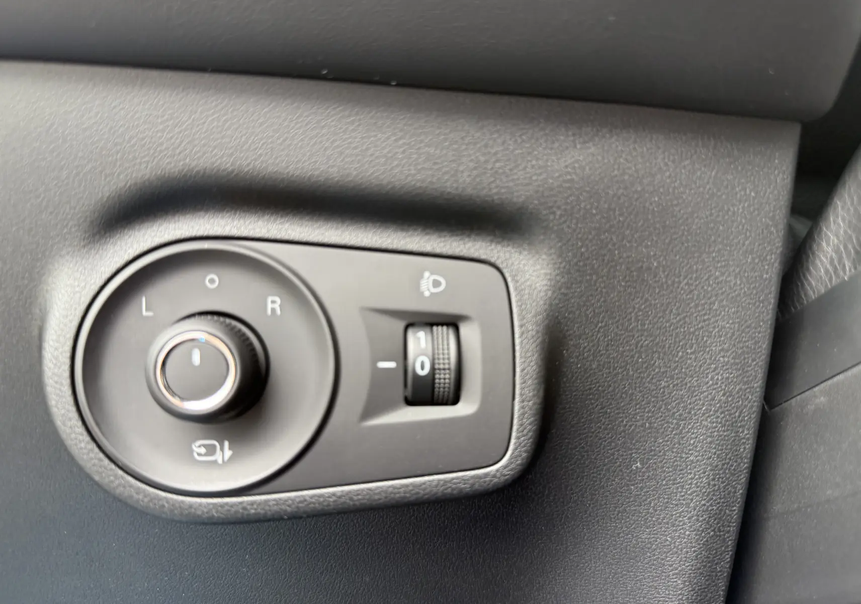 Gros plan sur les commandes de réglage des rétroviseurs et de l'éclairage du tableau de bord intérieur du MG Motor ZS Pebble Black.