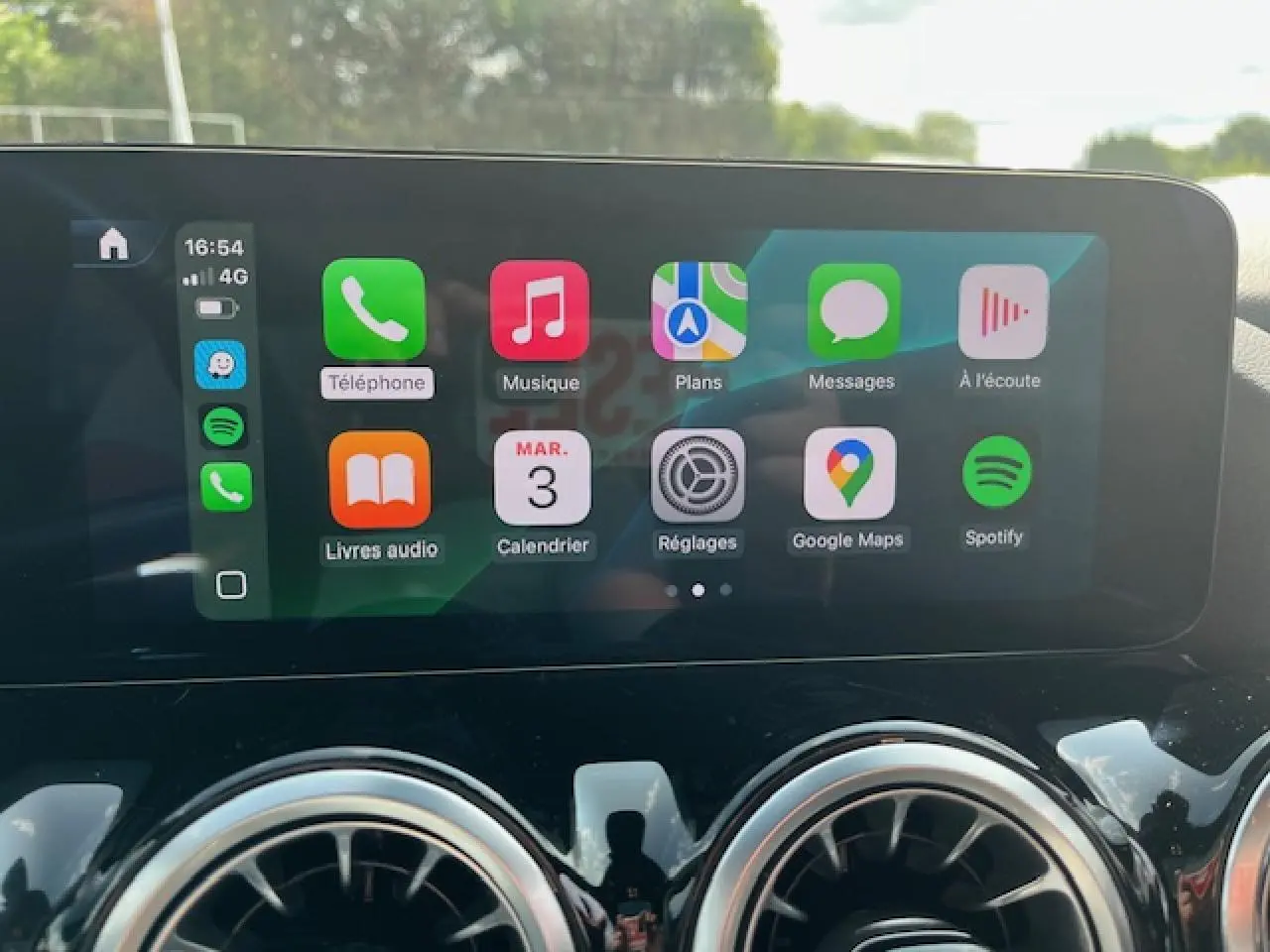 Écran tactile central affichant Apple CarPlay dans l'habitacle d'une Mercedes GLA 250 e blanche 2024.