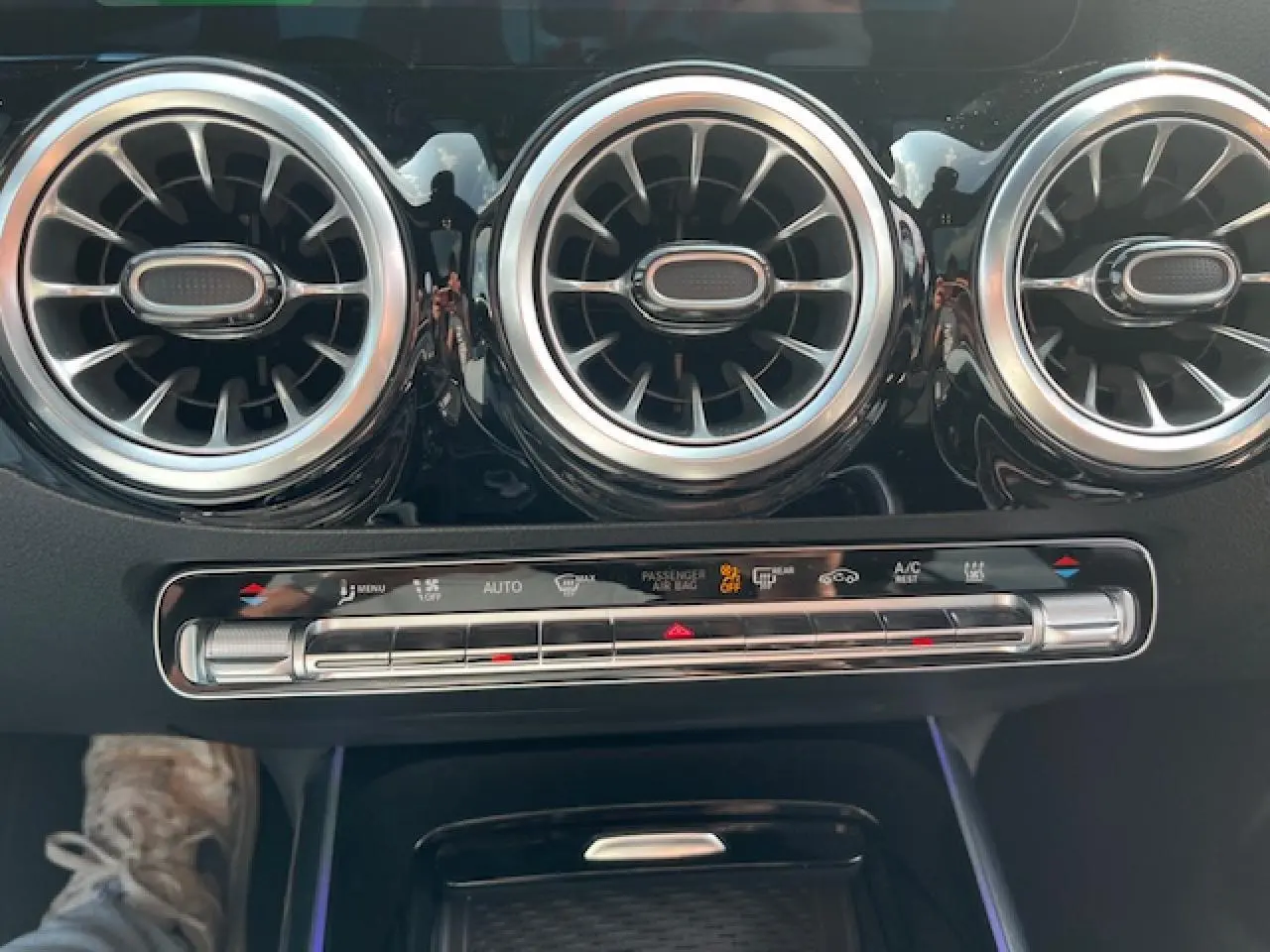 Détail de la sortie d'air ronde chromée et commandes de climatisation dans l'habitacle du Mercedes GLA blanc 2024.