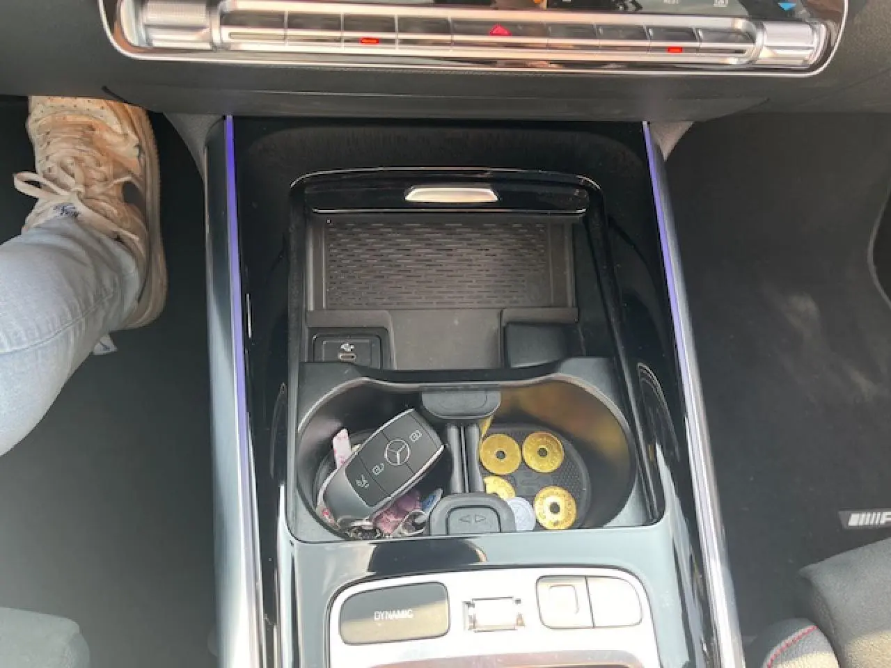 Vue plongeante sur la console centrale noire brillante du Mercedes GLA 250 e hybride avec clé et pièces dans les porte-gobelets.