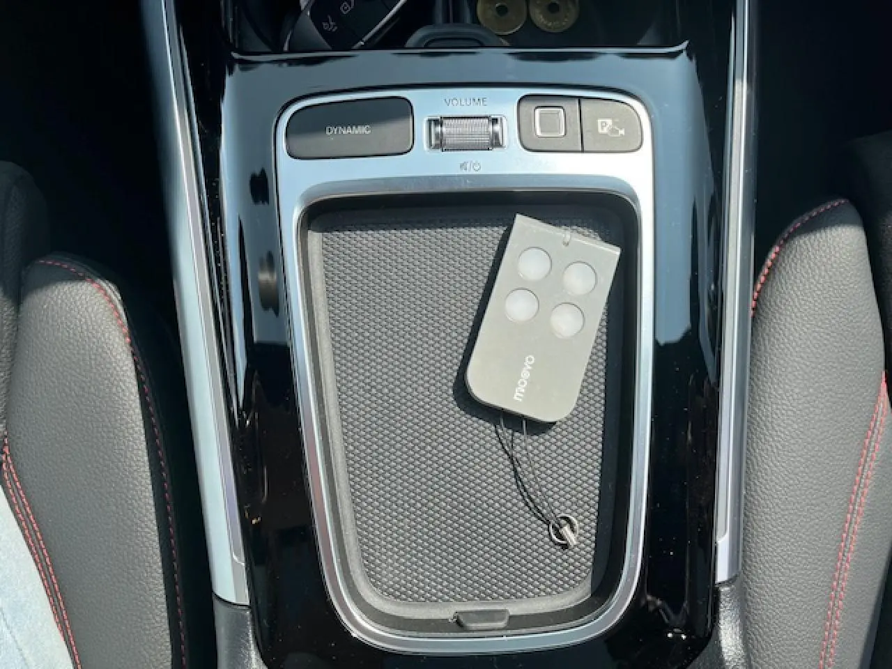 Vue plongeante sur la console centrale noire brillante du Mercedes GLA 250 e AMG Line avec télécommande posée.