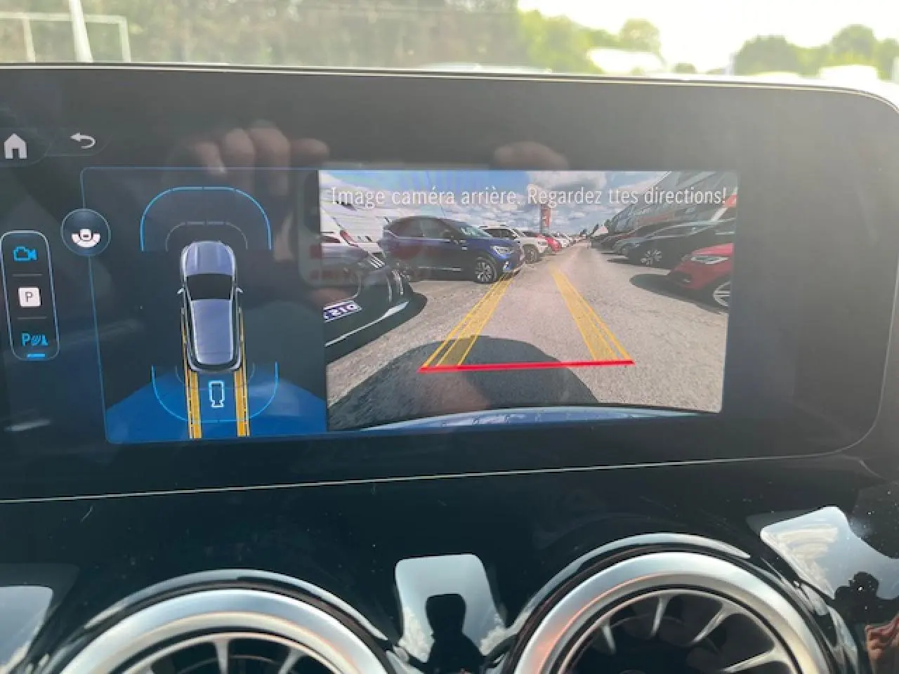 Écran multimédia du Mercedes GLA 250 e blanc 2024 montrant la caméra de recul et l'aide au stationnement