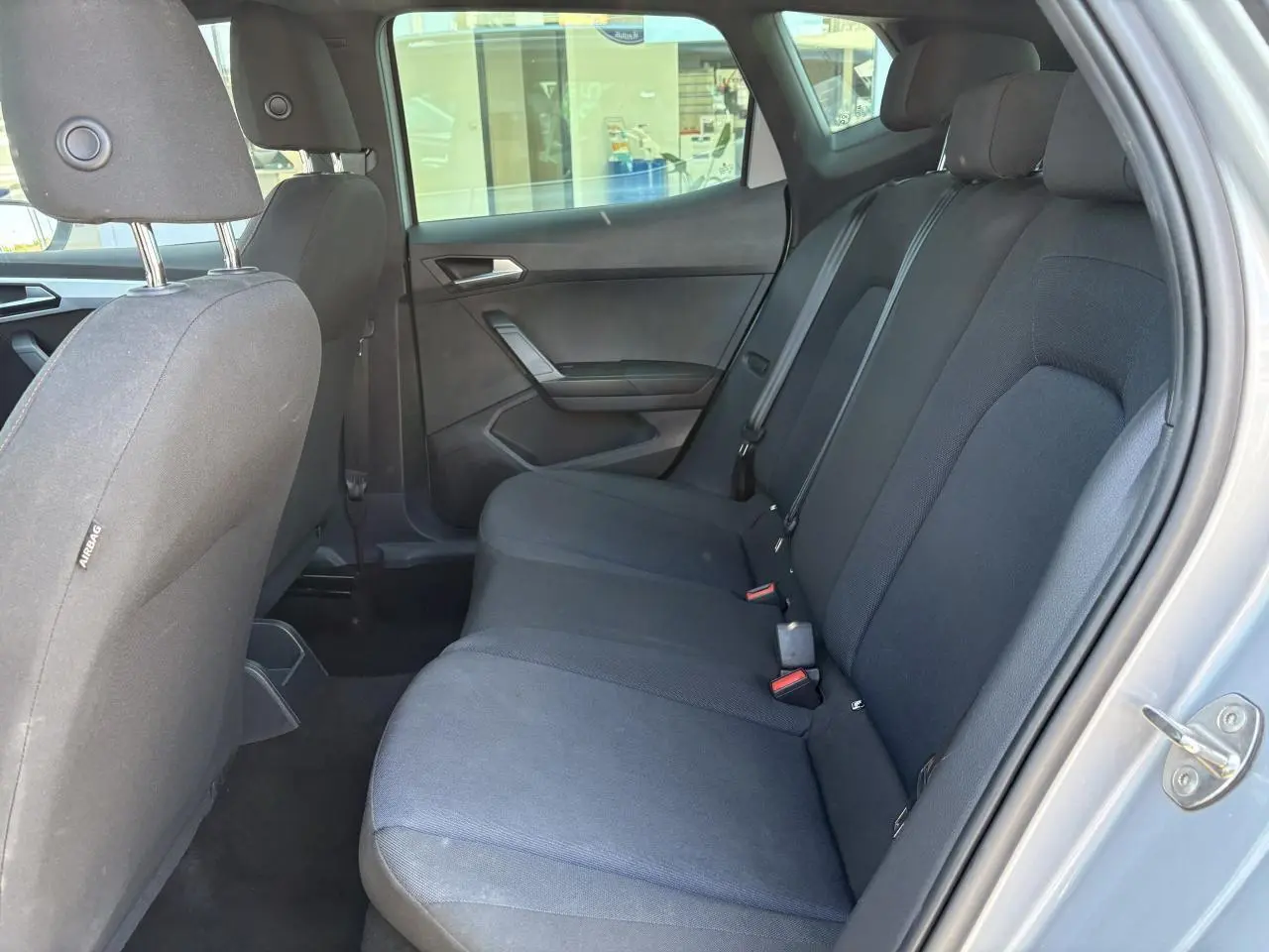 Vue intérieure côté droit sur la banquette arrière textile noire du SEAT ARONA 2024 avec appuie-têtes et ceintures visibles.