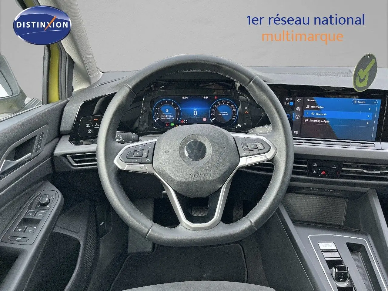 Vue intérieure centrée sur le volant et le tableau de bord numérique d'une Volkswagen Golf jaune 2020.