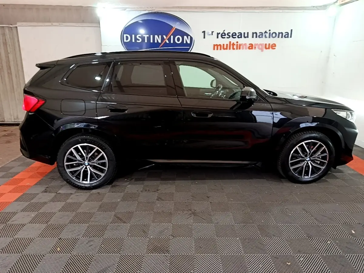 BMW X1 xDrive23i M Sport noir, vue profil côté gauche, jantes alliage et vitres teintées visibles.