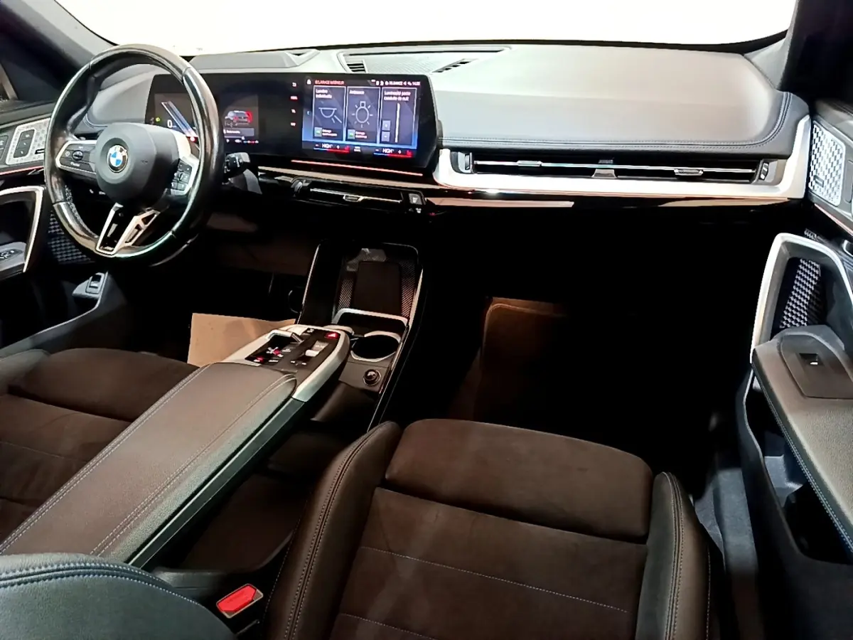 Vue intérieure avant droite du BMW X1 xDrive23i M Sport 2023, tableau de bord numérique et volant cuir noir.