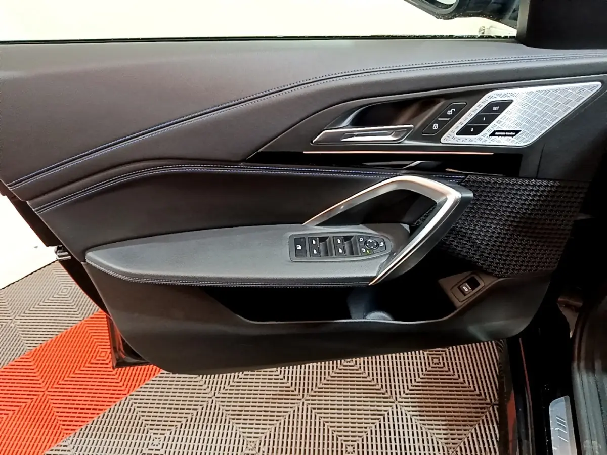 Vue latérale du panneau de porte conducteur noir avec commandes vitres et insert décoratif argenté du BMW X1 xDrive23i M Sport 2023.