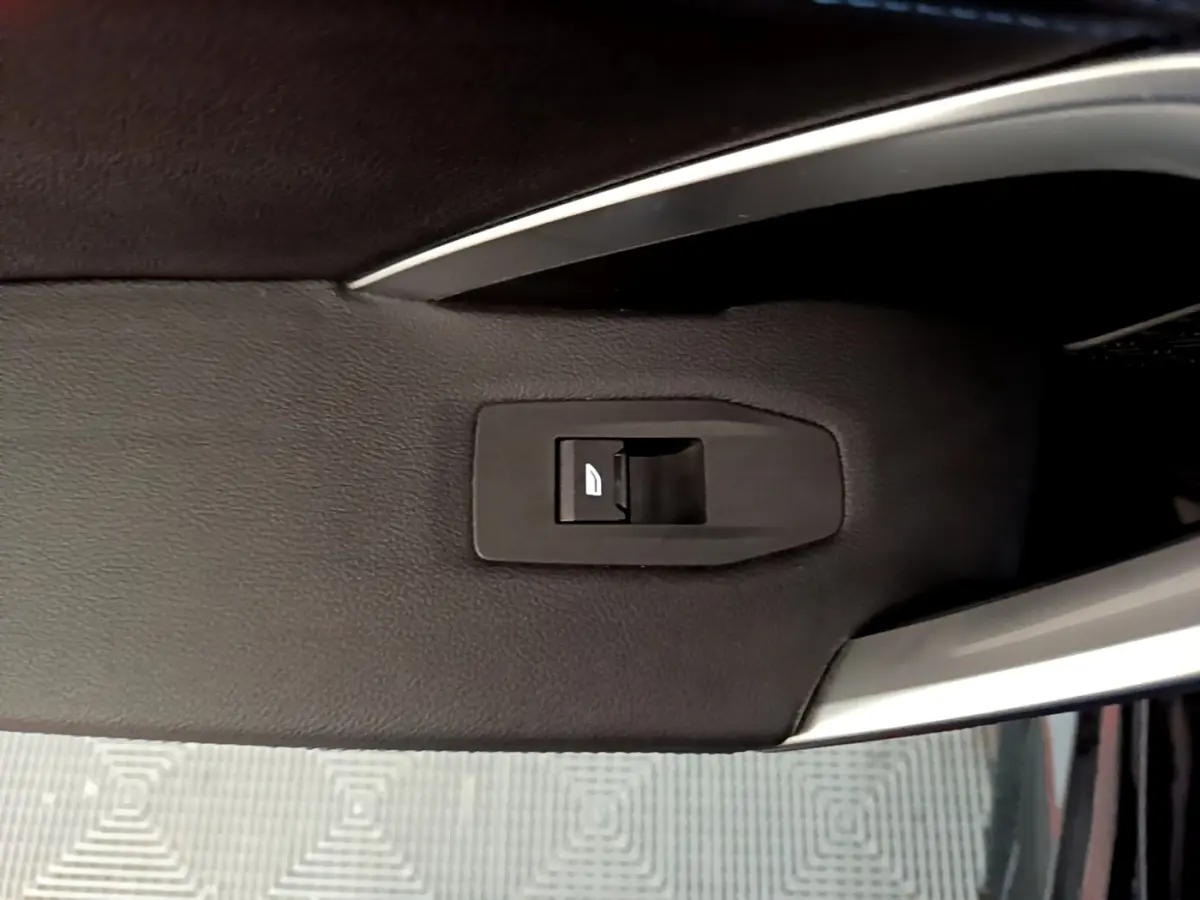 Bouton de commande de lève-vitre sur la porte intérieure côté conducteur d’un BMW X1 noir, version 2023.