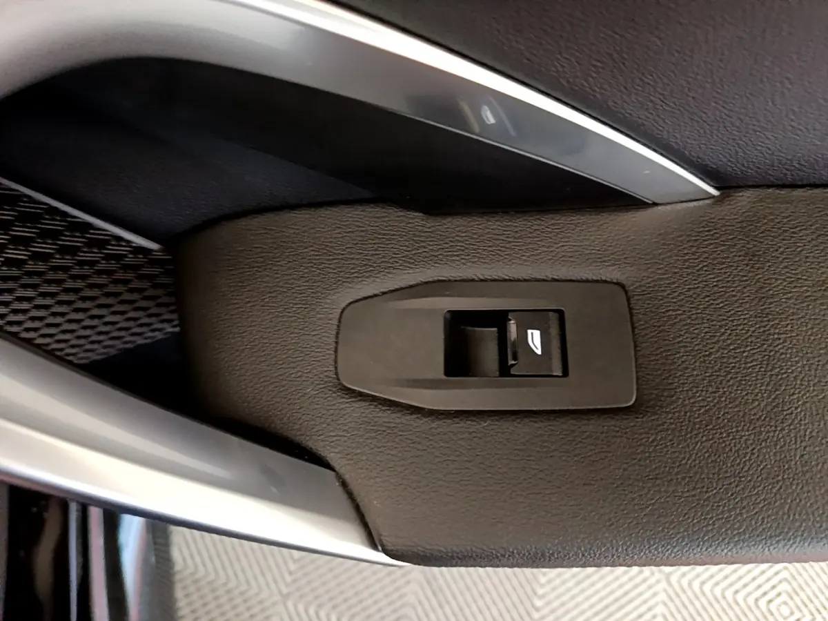 Détail de la commande de lève-vitre sur la porte intérieure en cuir noir du BMW X1 xDrive23i M Sport 2023.