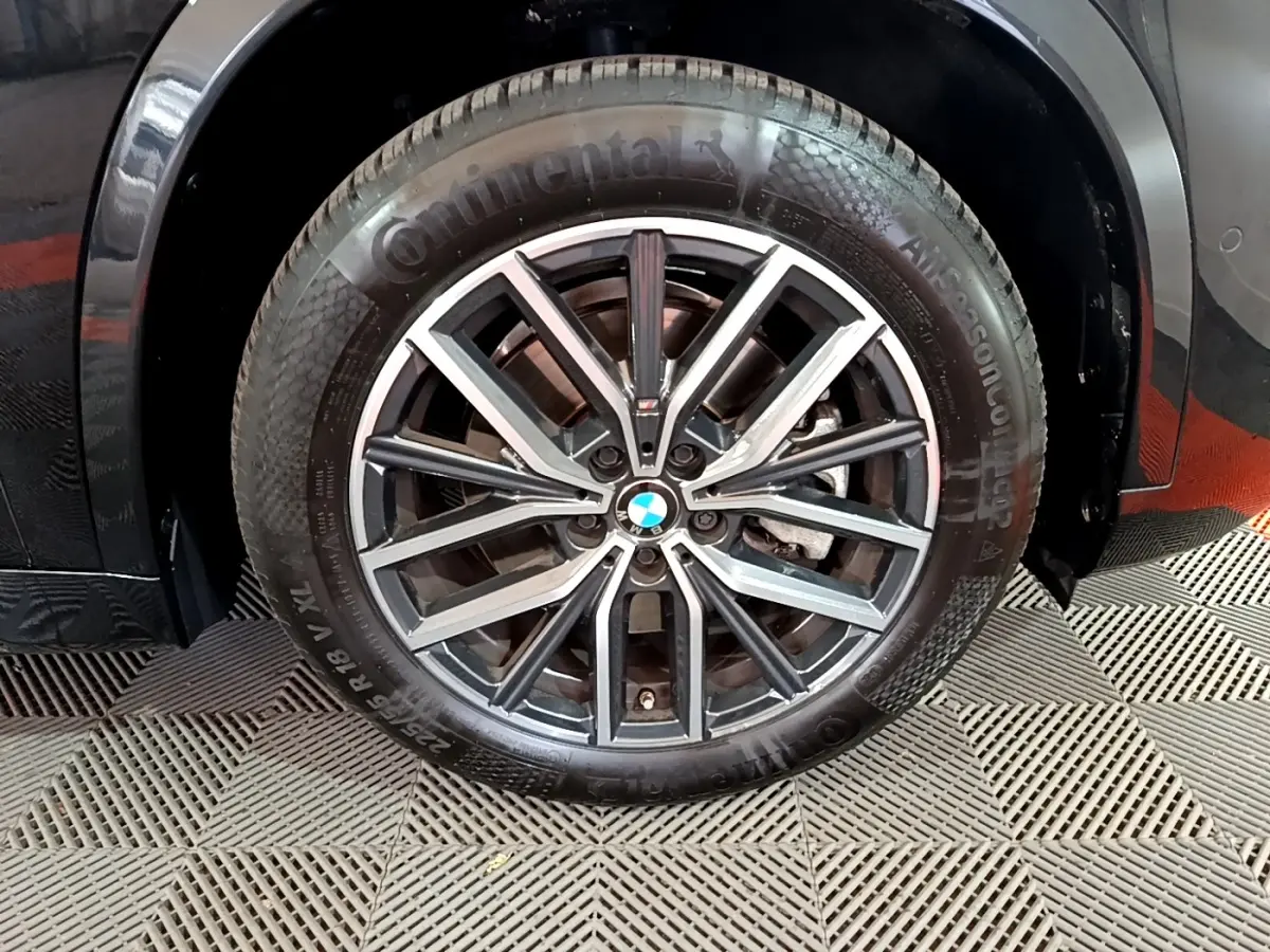 Gros plan sur la roue avant droite noire d’un BMW X1 xDrive23i M Sport 2023 avec jante alliage multibranches.