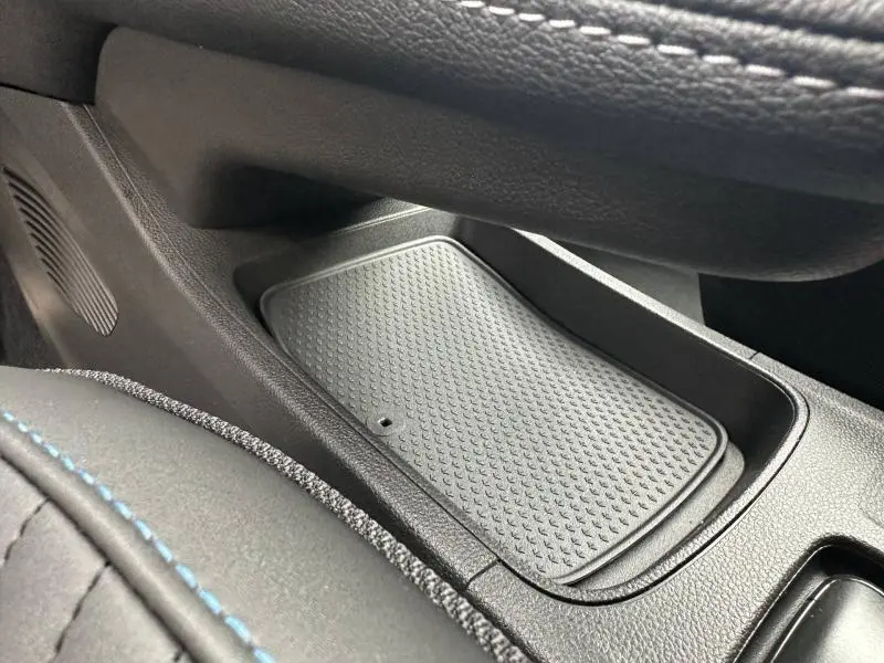 Gros plan sur le rangement central intérieur du Renault Captur 1.8 E-Tech hybride, avec surpiqûres bleues sur le cuir noir.