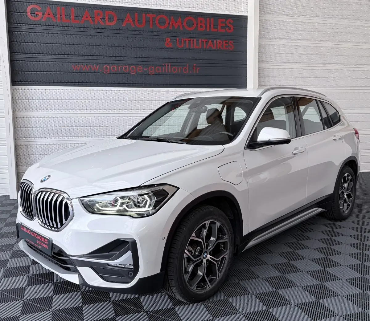 Vue 3/4 avant droite d’un BMW X1 xDrive25eA xLine blanc avec calandre chromée et jantes alliage distinctives.