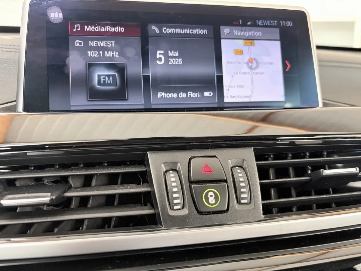 Gros plan sur l’écran tactile central et les commandes de ventilation du tableau de bord du BMW X1 blanc xDrive25eA xLine 2021.