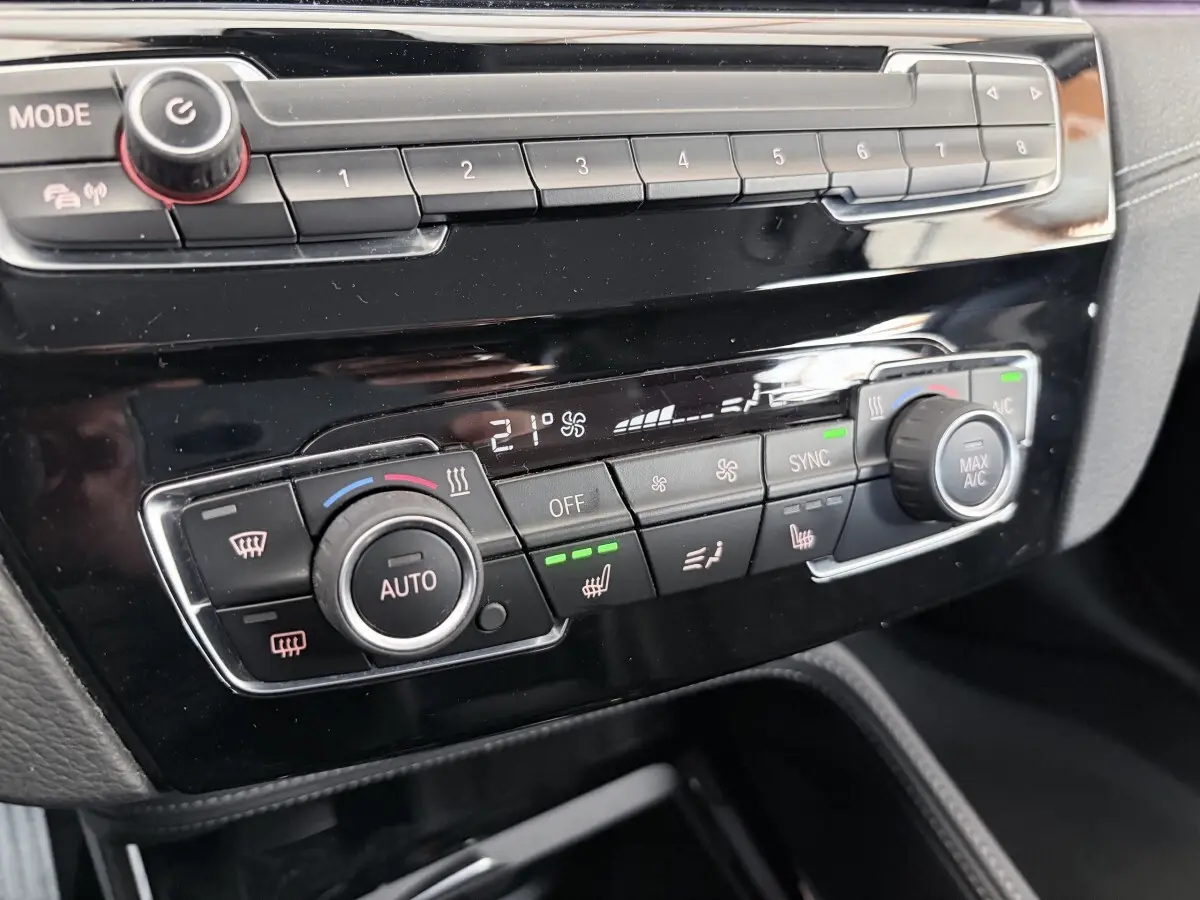 Détail de la console centrale noire du BMW X1 xDrive25eA xLine 2021 montrant les commandes de climatisation automatique et sièges chauffants.