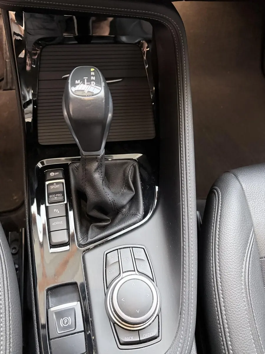 Vue rapprochée de la console centrale noire du BMW X1 xDrive25eA 2021 avec levier de vitesses et commandes multimodes.