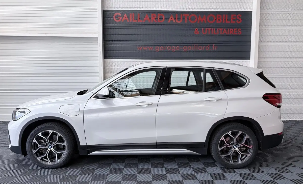 Profil droit d’un BMW X1 blanc hybride rechargeable xDrive25eA xLine 2021, avec jantes alliage et prises de charge latérales.