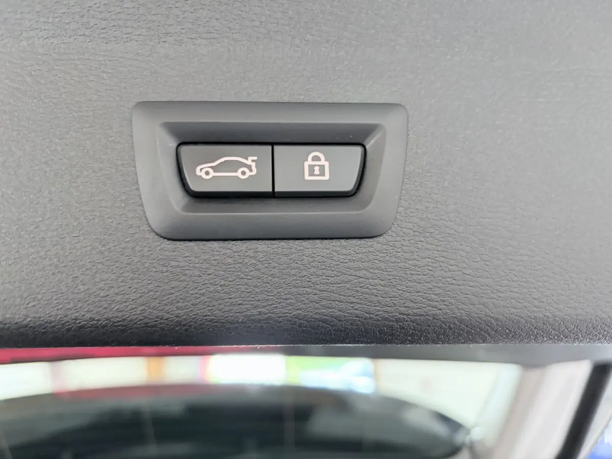 Gros plan sur les boutons d'ouverture et de verrouillage du coffre du BMW X1 blanc xDrive25eA xLine 2021.