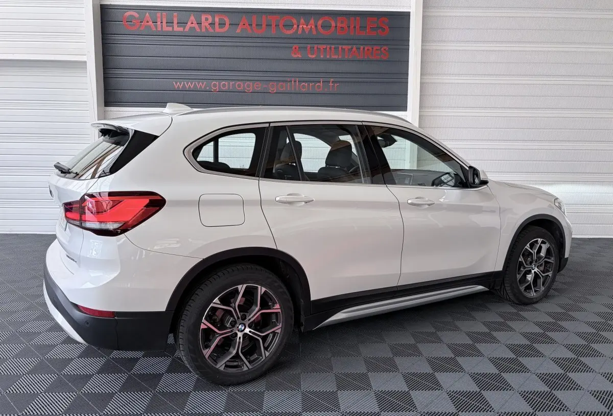 BMW X1 xDrive25eA xLine blanc en vue latérale droite, avec jantes alliage et rails de toit chromés visibles.