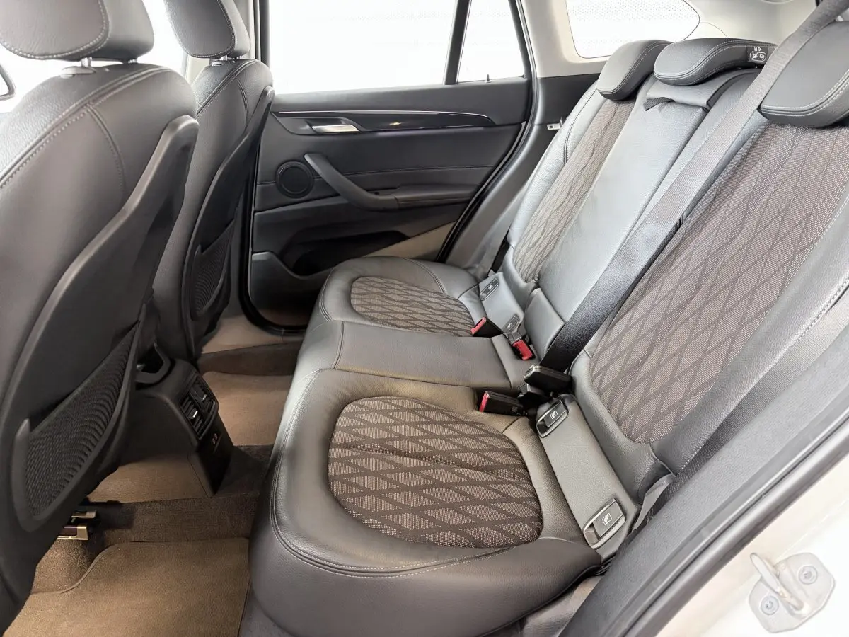 Vue intérieure arrière côté droit montrant les sièges en cuir noir et tissu gris du BMW X1 blanc 2021.