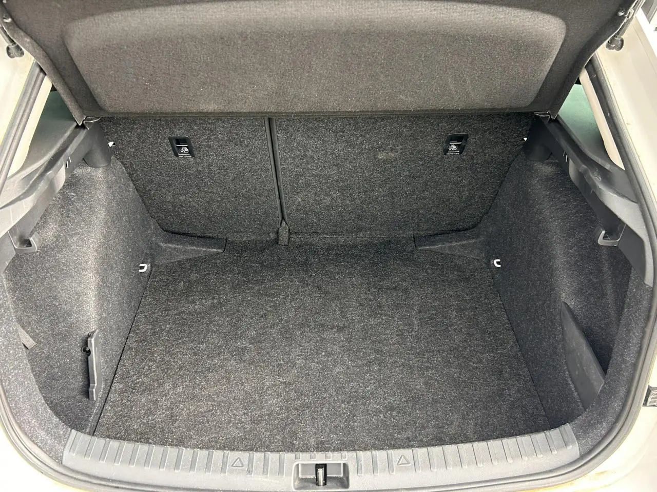 Coffre ouvert vu de l'arrière d'une Skoda Scala TSI 116 DSG7 blanc Candy, intérieur tapis gris foncé.