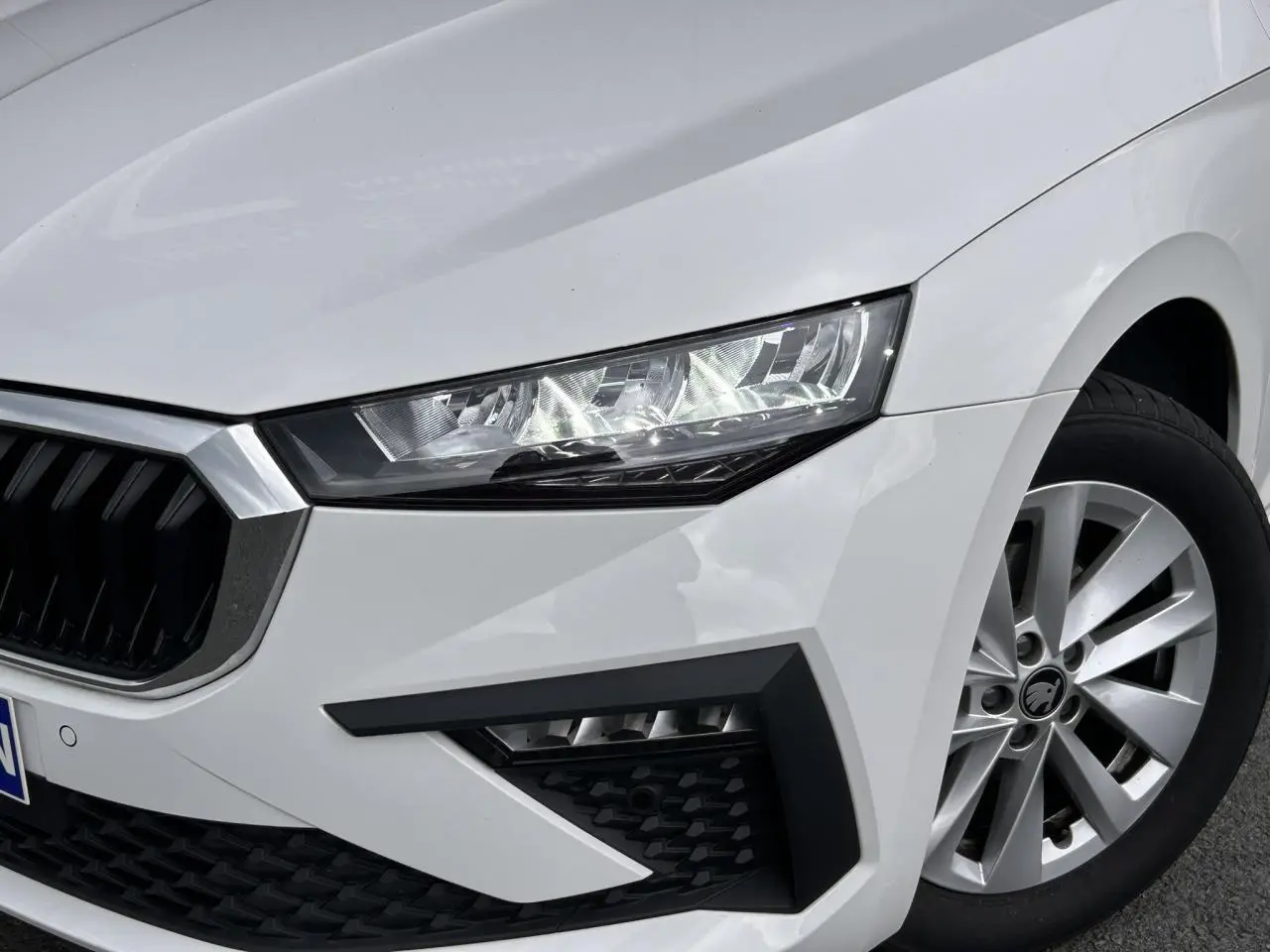 Gros plan sur l'avant droit blanc Candy d'une Skoda Scala 2025, mettant en valeur le phare LED et la jante alliage 16 pouces.