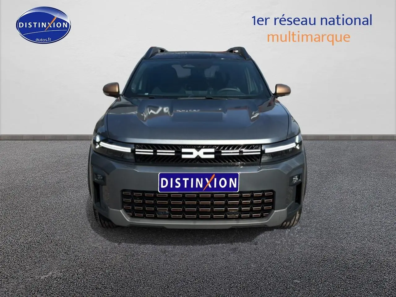 Vue frontale du Dacia Bigster gris schiste avec calandre noire et phares LED fins allumés.