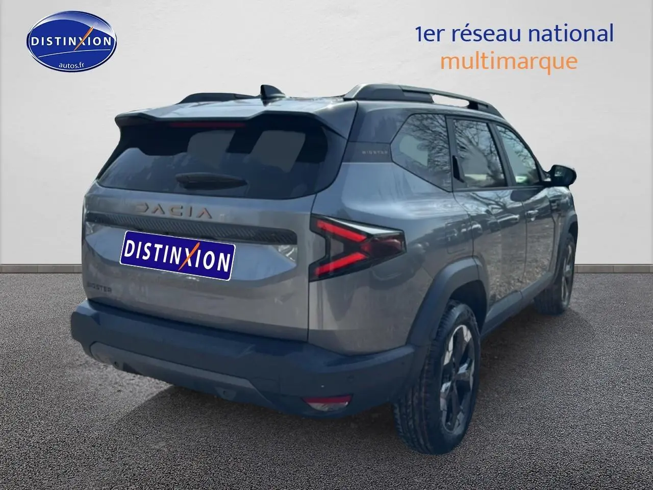 Vue 3/4 arrière droit du SUV Dacia Bigster gris schiste avec barres de toit et feux arrière LED en forme de flèche.