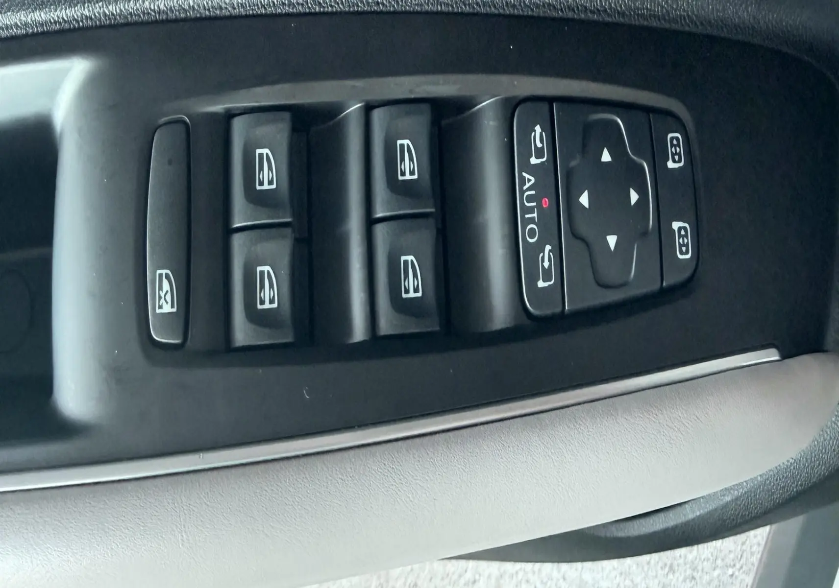 Gros plan sur les commandes des vitres électriques et rétroviseurs côté conducteur d’un Renault Koleos blanc.
