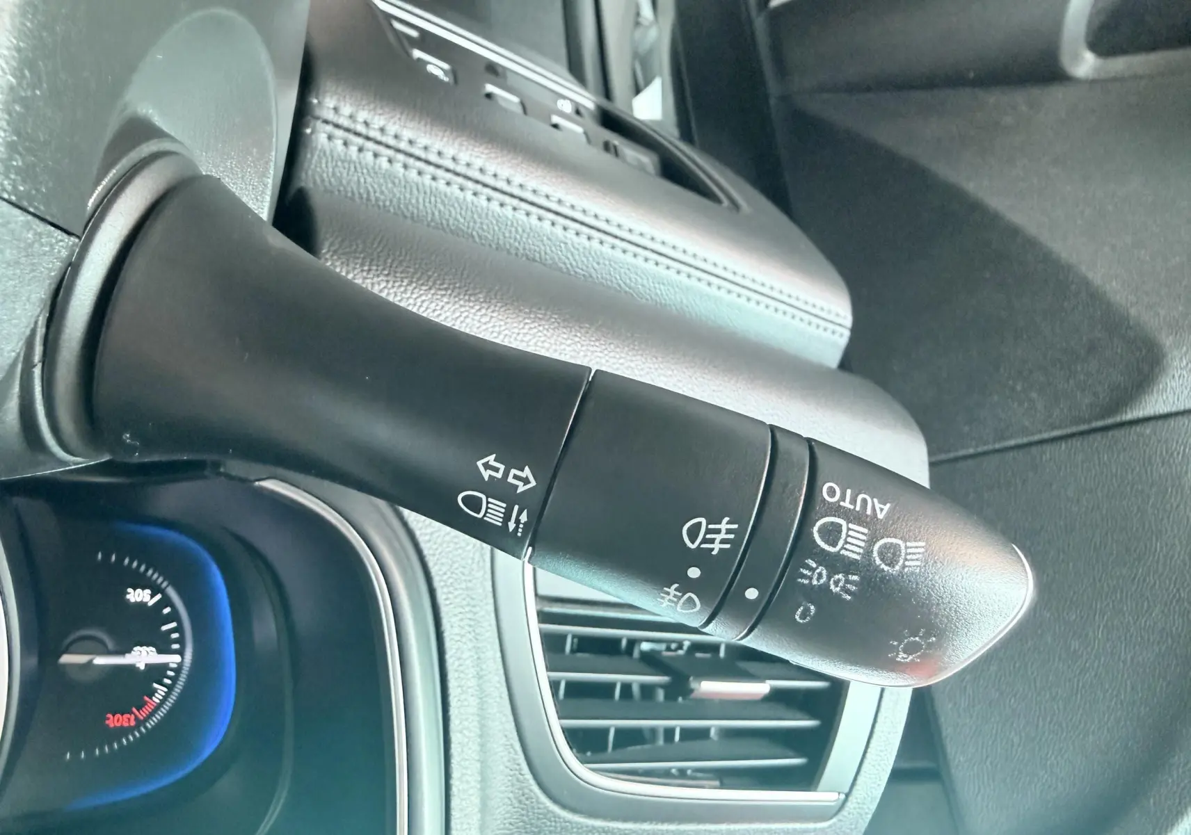 Gros plan sur la commande des phares et clignotants du Renault Koleos TCE 160 Initial Paris, intérieur noir.