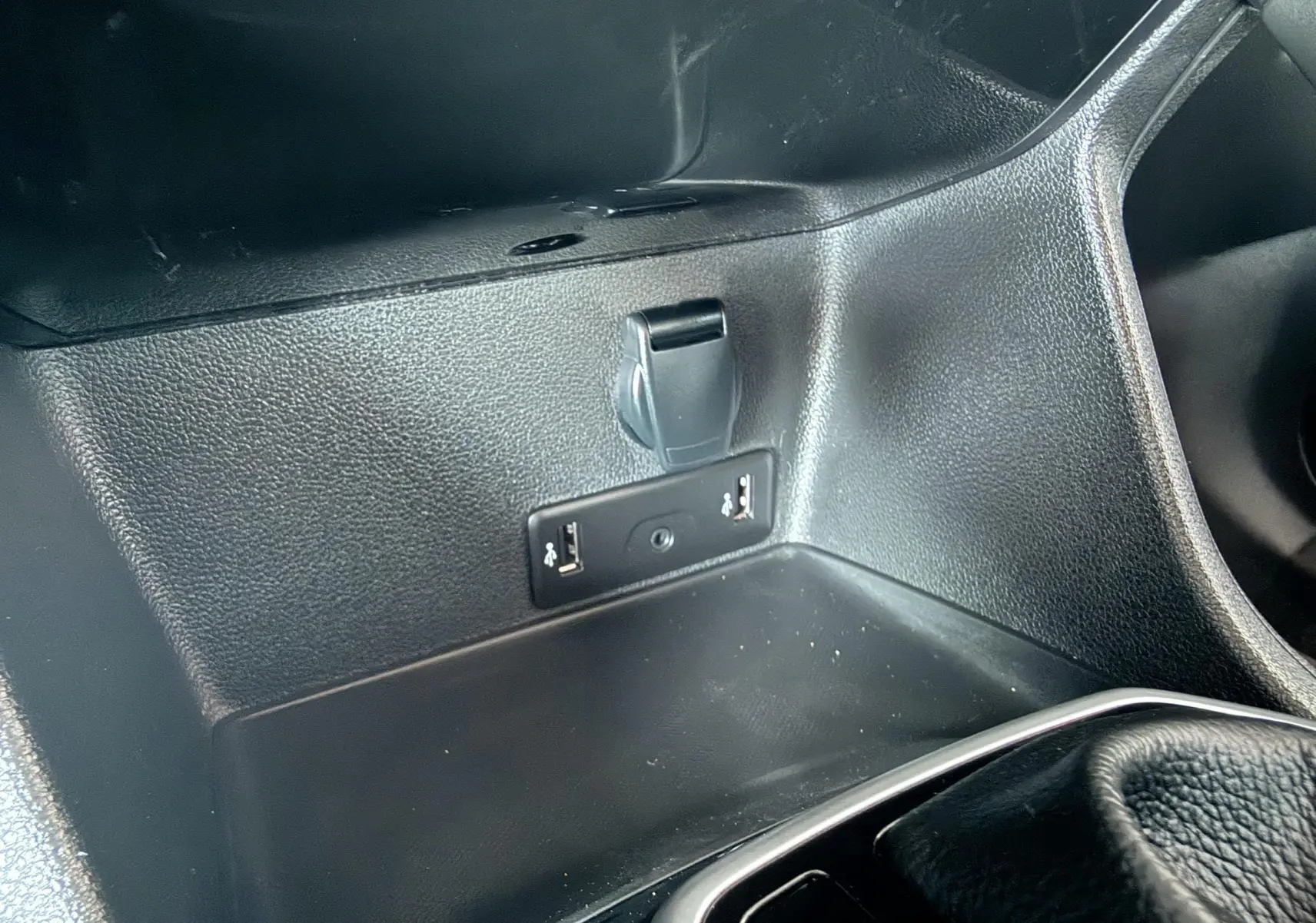 Prise USB et prise 12V en gros plan dans la console centrale d’un Renault Koleos TCE 160 blanc, intérieur noir.