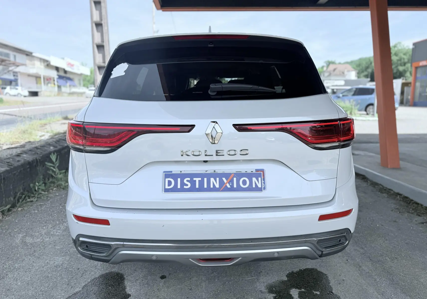 Vue arrière d'un Renault Koleos blanc 2021 avec feux arrière étirés et logo au centre du hayon.