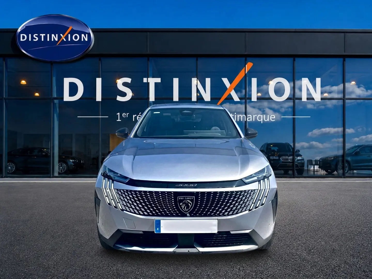 Vue frontale d’un Peugeot 3008 gris 2025 avec calandre distinctive et logo lion, devant une vitrine Distinxion.