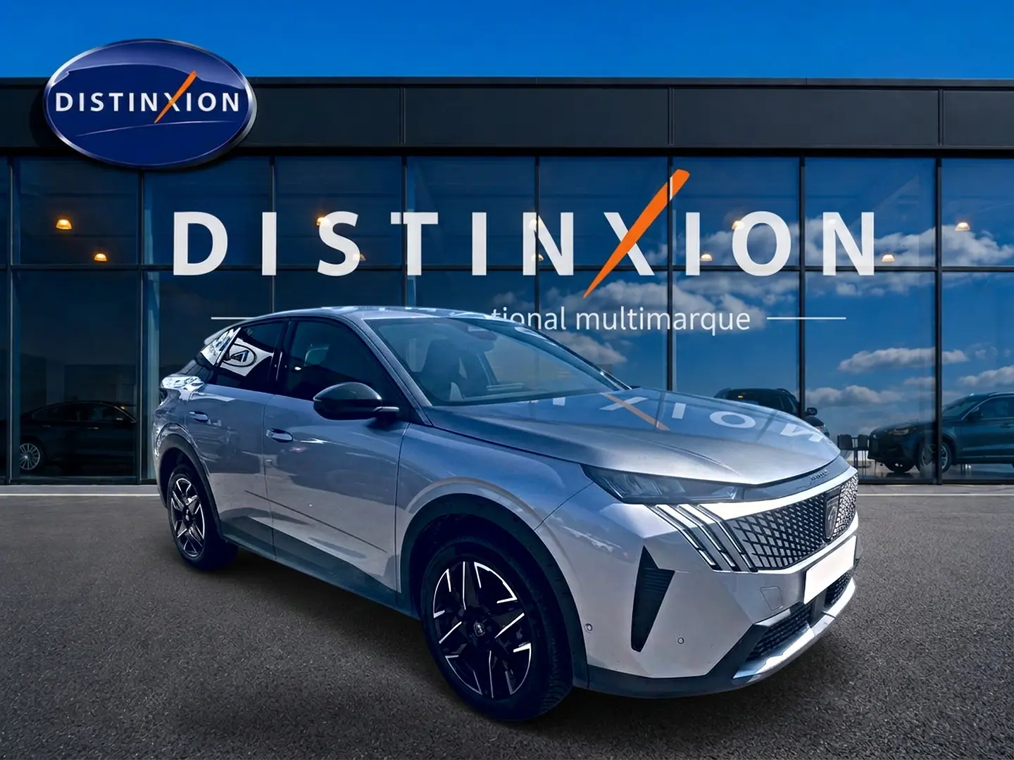 Peugeot 3008 gris en 3/4 avant droit, avec calandre distinctive et jantes alliage noires devant un showroom.