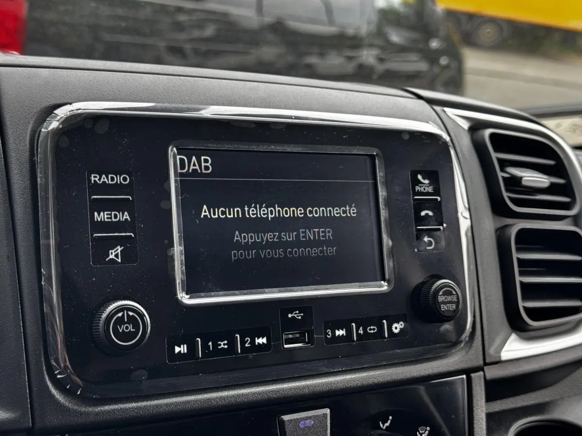 Gros plan sur l’écran tactile central noir du tableau de bord du Peugeot Boxer Fourgon blanc, avec commandes radio visibles.