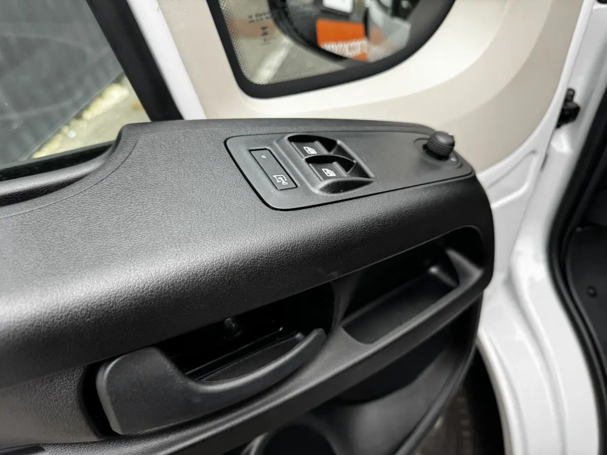 Gros plan sur la porte avant gauche blanche du Peugeot Boxer Fourgon, avec commandes électriques des vitres et rétroviseur.