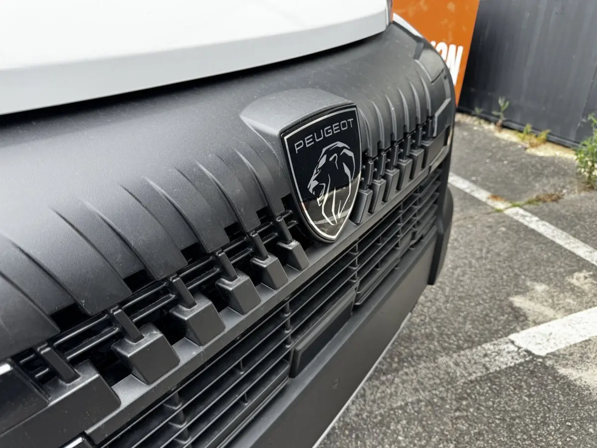 Gros plan sur la calandre noire et le logo Peugeot du fourgon blanc Peugeot Boxer L2H2 Diesel 2026.