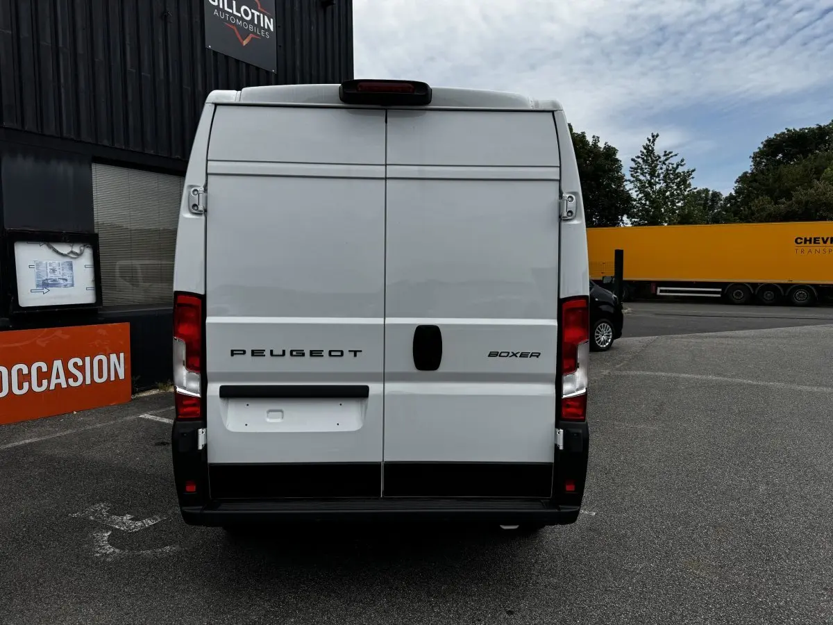 Vue arrière d’un Peugeot Boxer Fourgon blanc, avec portes battantes fermées et feux arrière rouges visibles.