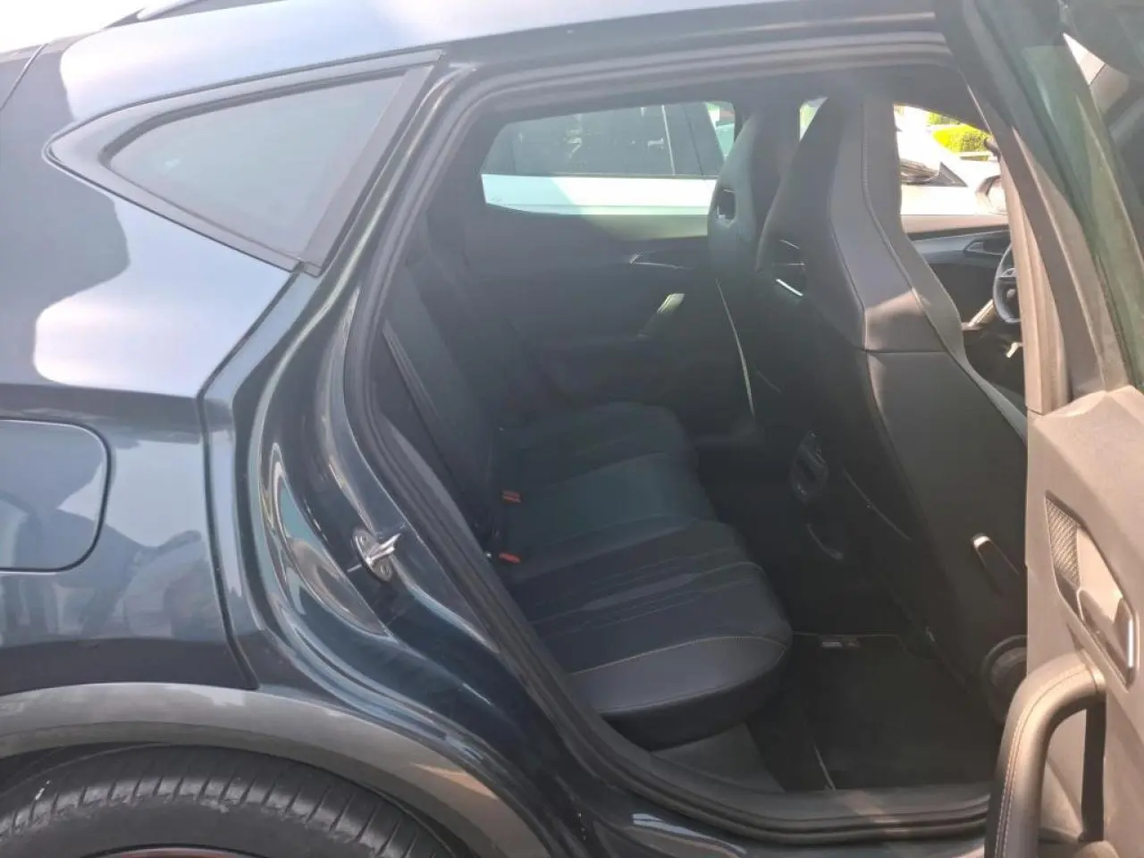 Vue côté gauche arrière sur l'intérieur du CUPRA Formentor gris, montrant les sièges arrière en textile noir et les portes ouvertes.