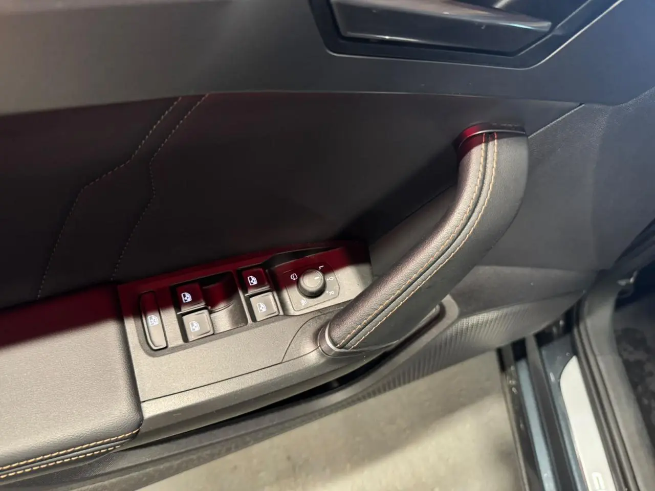 Détail de la porte côté conducteur du Cupra Formentor gris, avec commandes de vitres et poignée en cuir surpiqué.