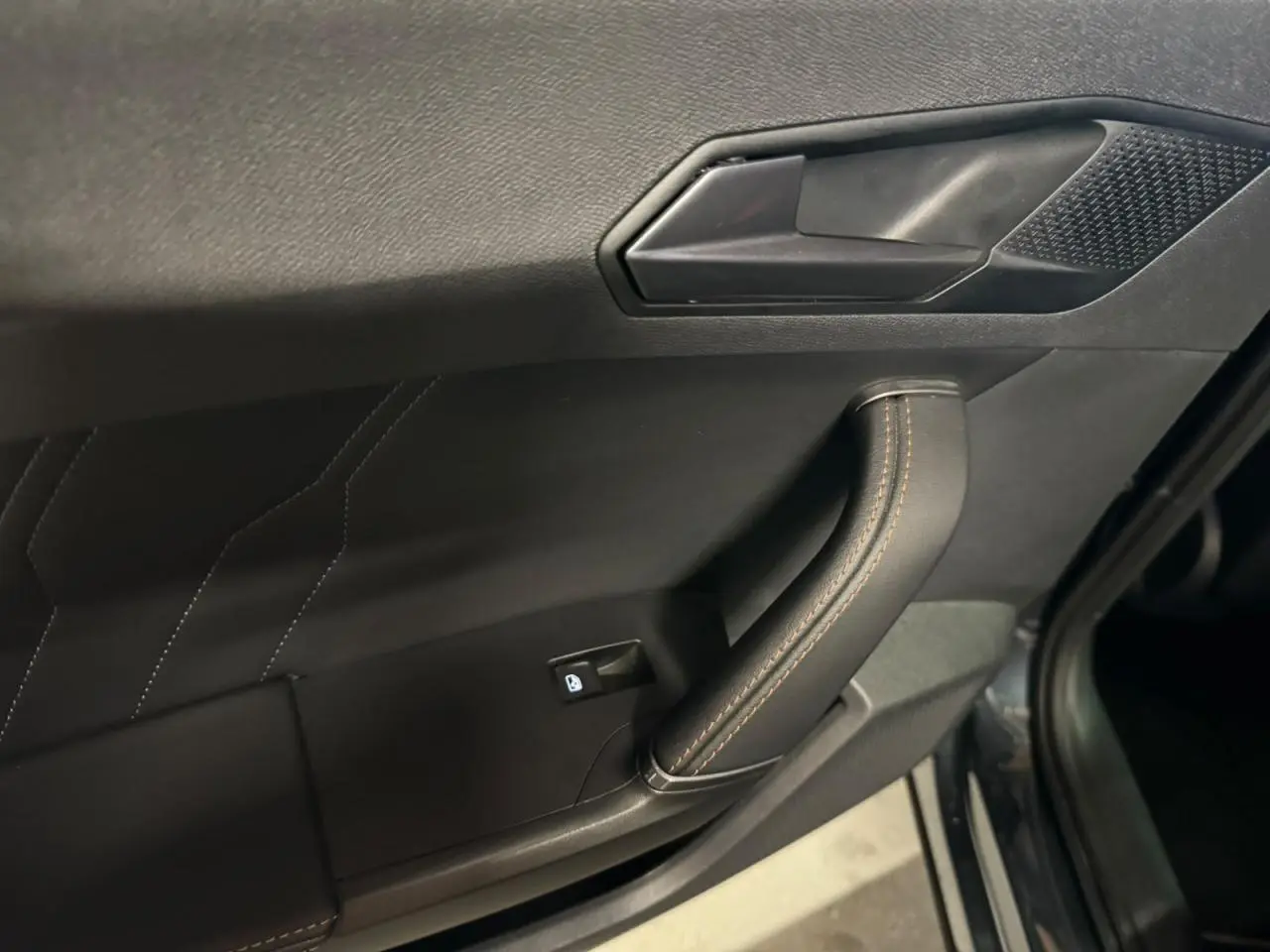 Poignée de porte intérieure côté gauche du Cupra Formentor gris, avec surpiqûres et bouton de verrouillage.