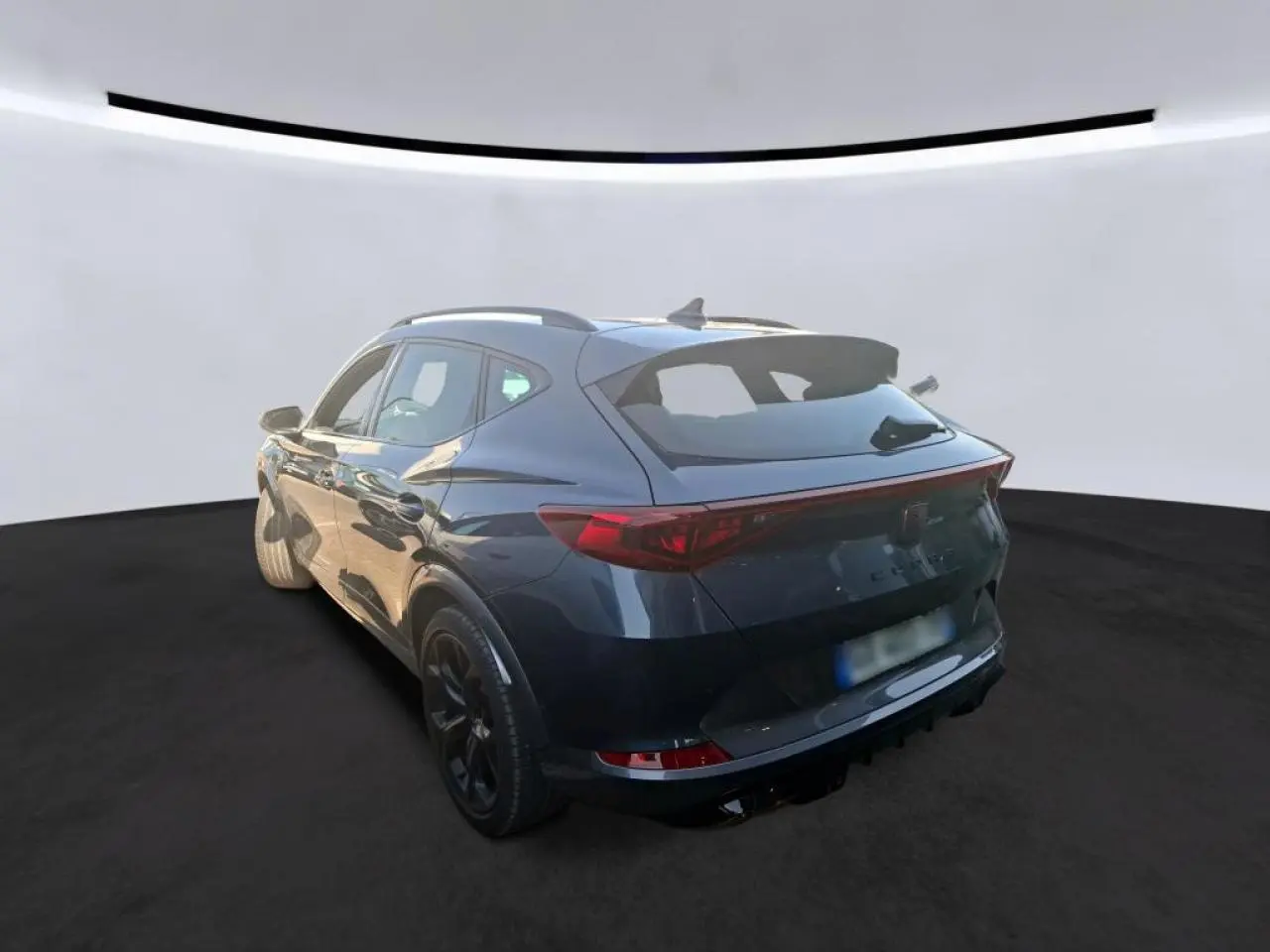 Vue 3/4 arrière droite du CUPRA Formentor gris avec jantes alliage noires et bandeau lumineux arrière LED.
