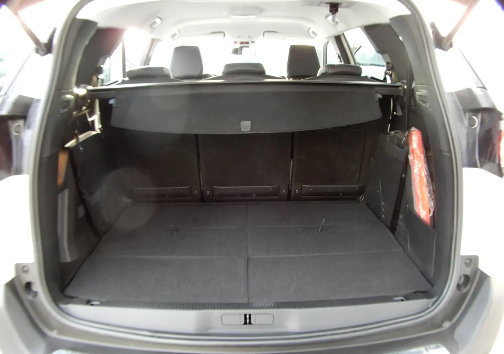 Coffre ouvert du Peugeot 5008 blanc nacré, vue arrière montrant l'espace de chargement et la tablette cache-bagages.