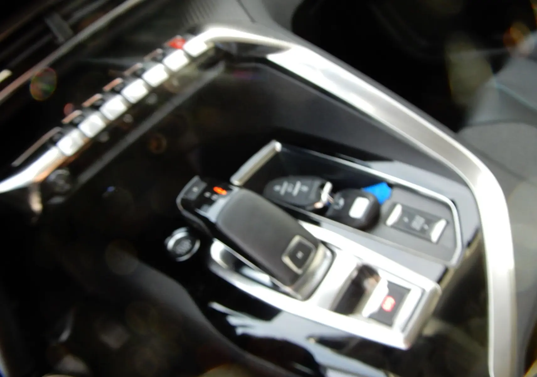 Gros plan sur la console centrale noire brillante du Peugeot 5008 blanc nacré, mettant en valeur le levier de vitesses automatique.