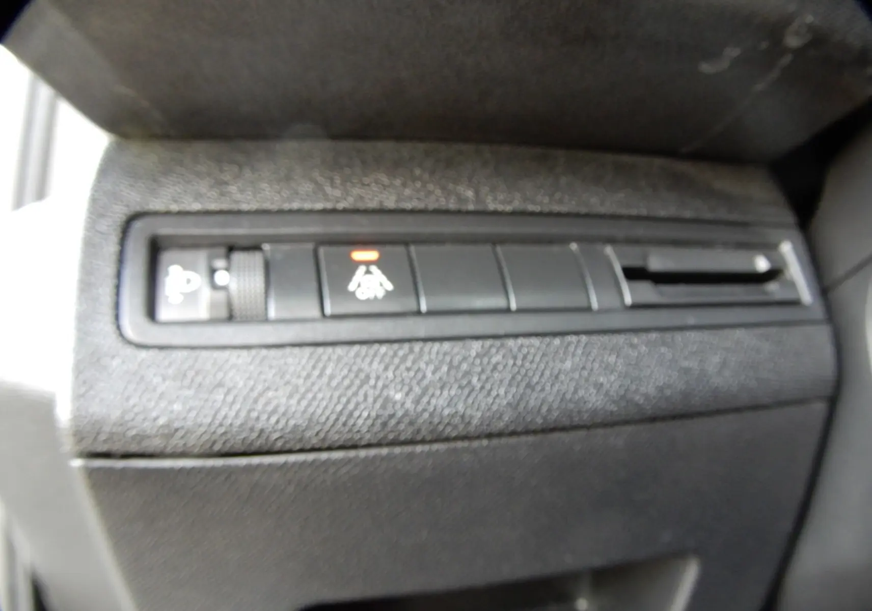 Gros plan sur les commandes noires du tableau de bord du Peugeot 5008 blanc nacré, avec un témoin orange allumé.