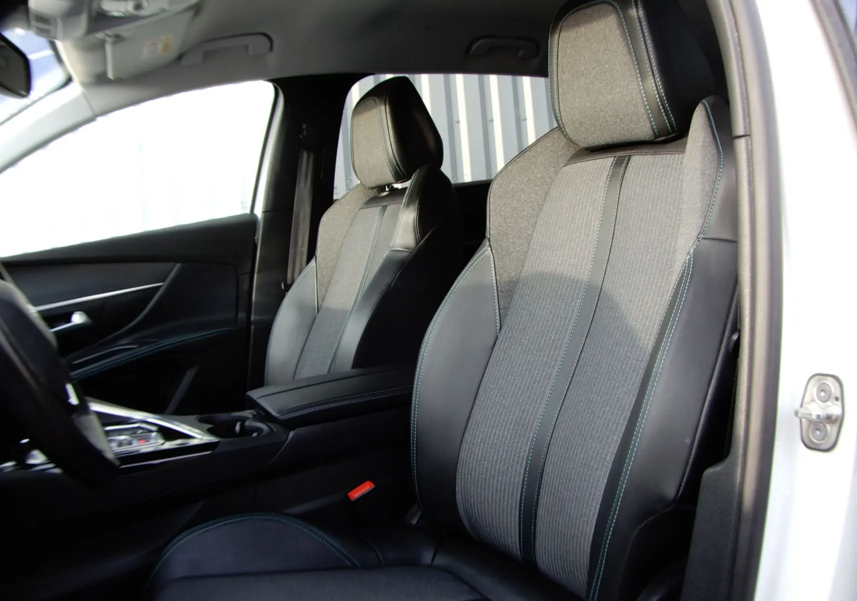 Vue intérieure côté droit du Peugeot 5008 blanc nacré 2021, sièges avant en tissu et cuir noir avec surpiqûres bleues.