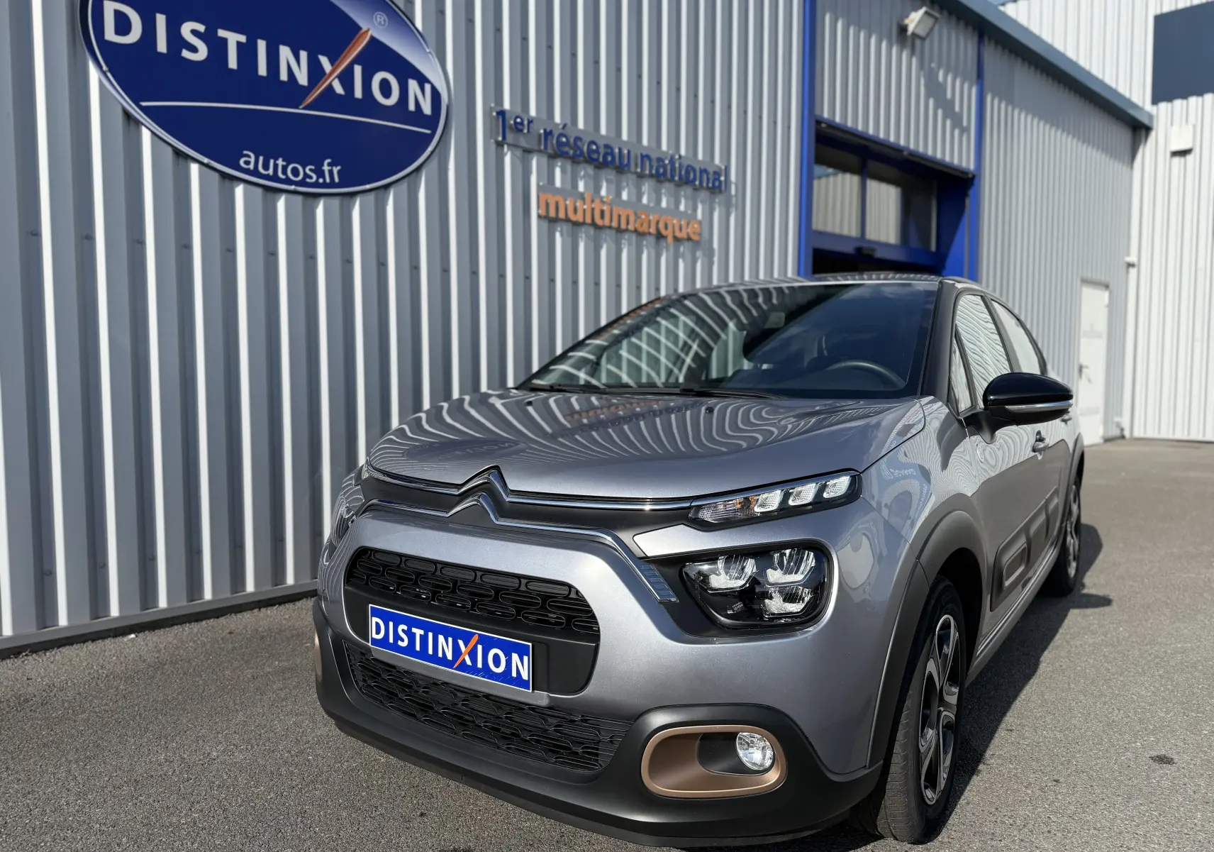 Citroën C3 gris acier vue 3/4 avant droit, avec phares LED et détails bronze autour des antibrouillards.