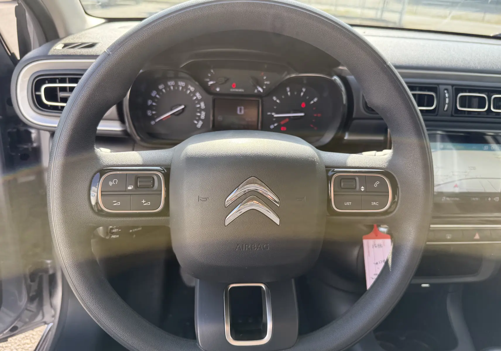 Vue frontale du volant noir de la Citroën C3 gris acier 2023, avec commandes intégrées et tableau de bord visible.