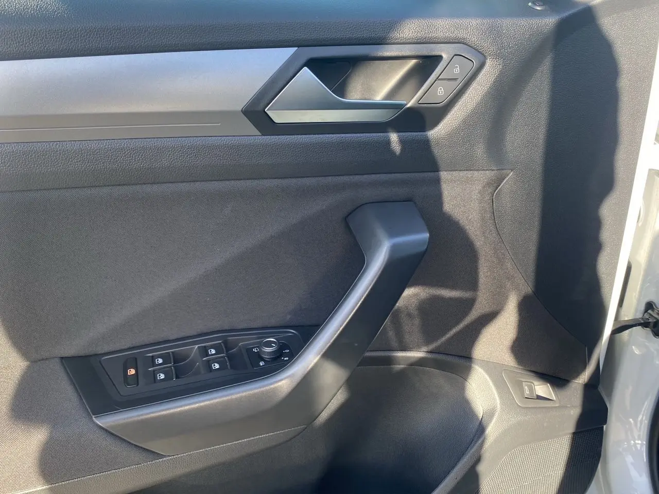 Vue rapprochée de la porte avant gauche intérieure du Volkswagen T-Roc Silver White avec commandes de vitres et serrure.
